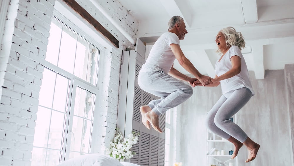 Older couple jumping on bed excitedly for free connection