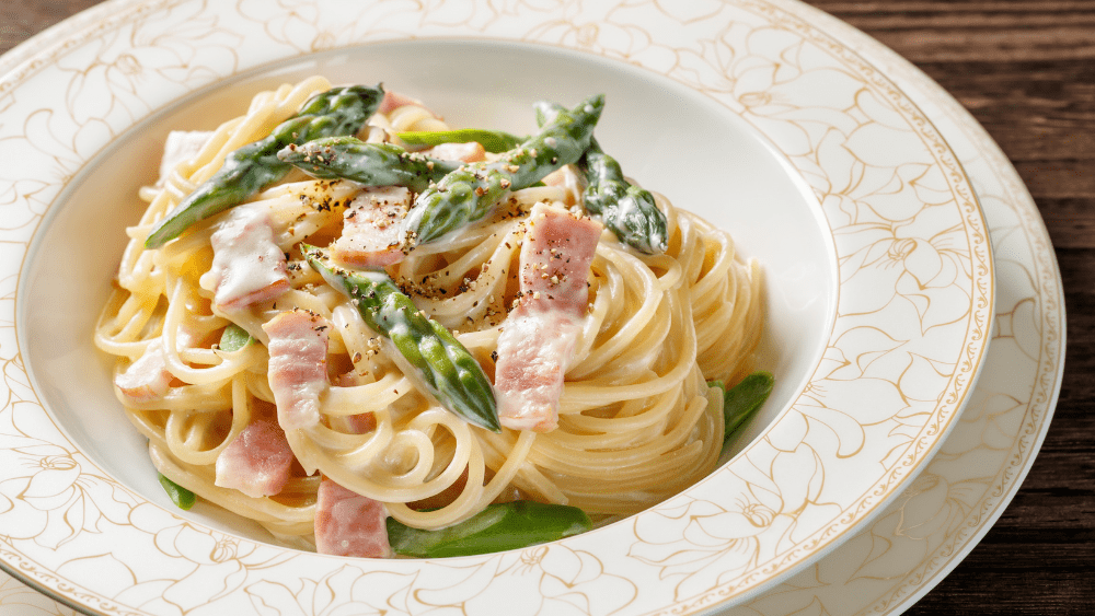 Spagetti carbonara with bacon and asparagus in a bowl.