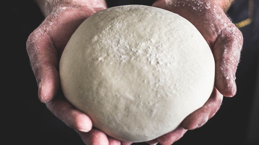 Pizza dough in hands.