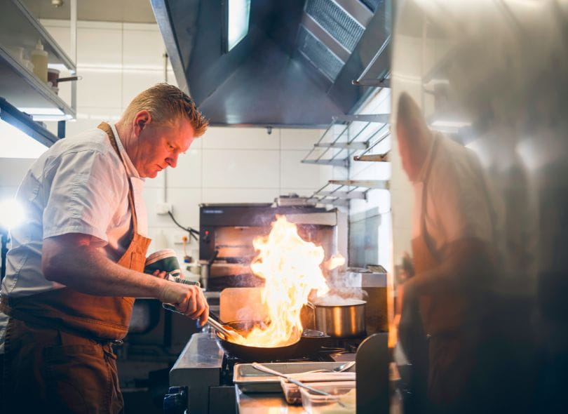 Chef Shaun Clouston cooking over open gas flame.