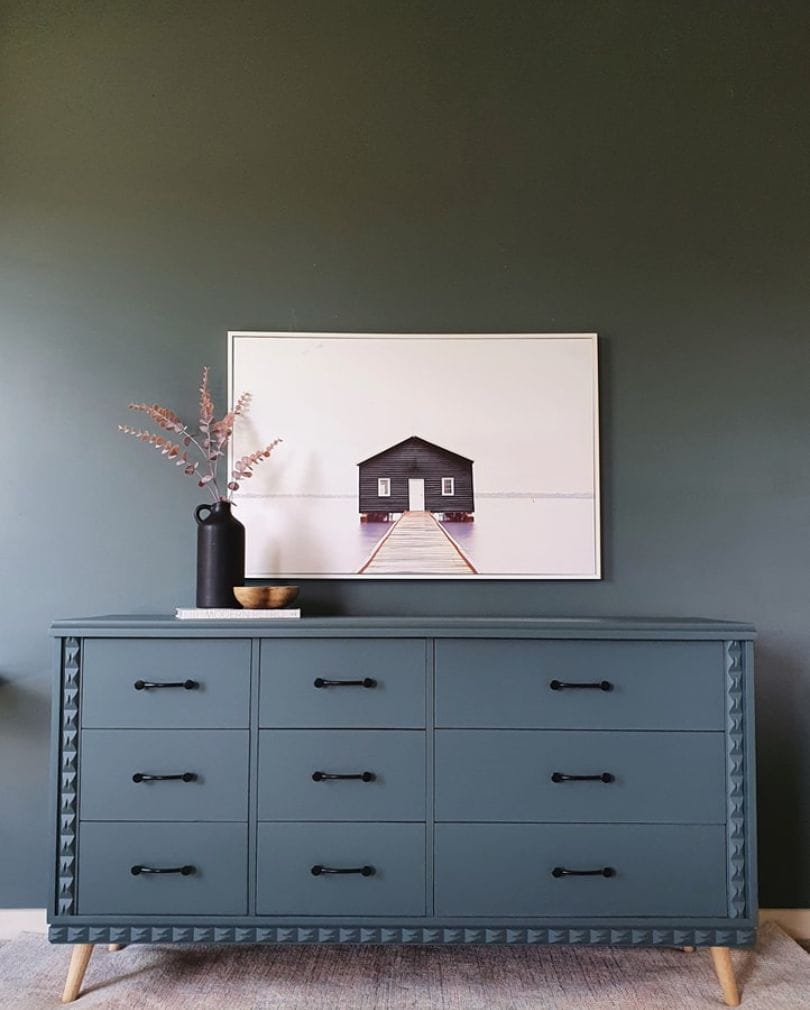 A blue sideboard in front of a blue wall.