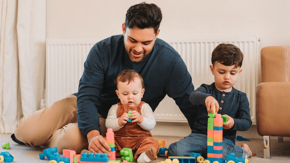 Dad playing with kids in front of natural gas radiator.