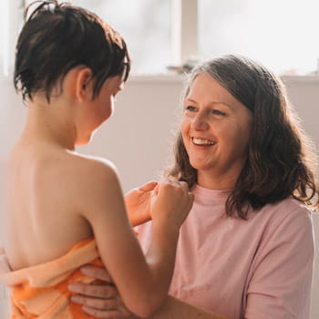 woman drying son with towel after shower