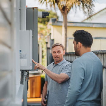 man pointing at gas meter on side of house