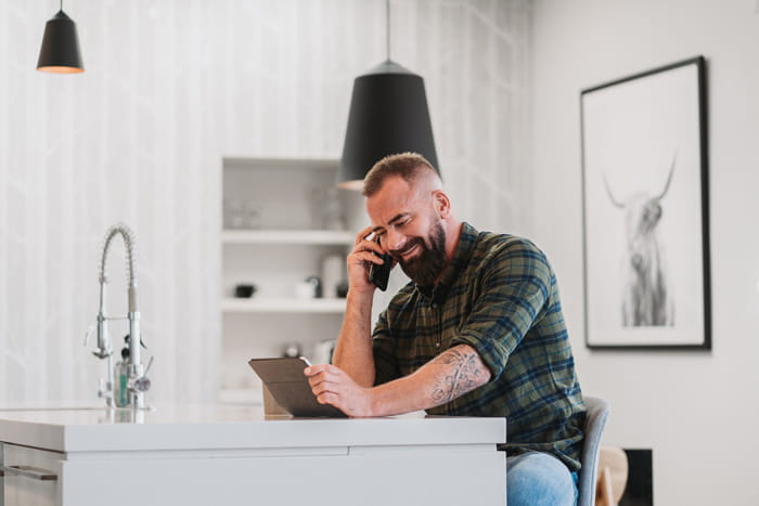 man sitting at kitchen table talking on phone