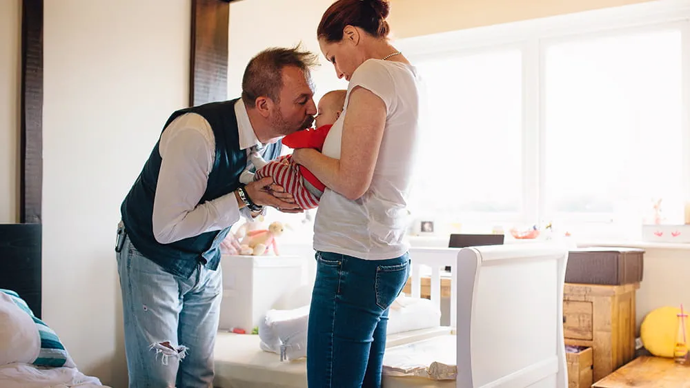 Father kissing baby held by mother