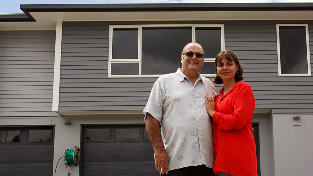 The OKanes in front of their rebuilt home powered by gas