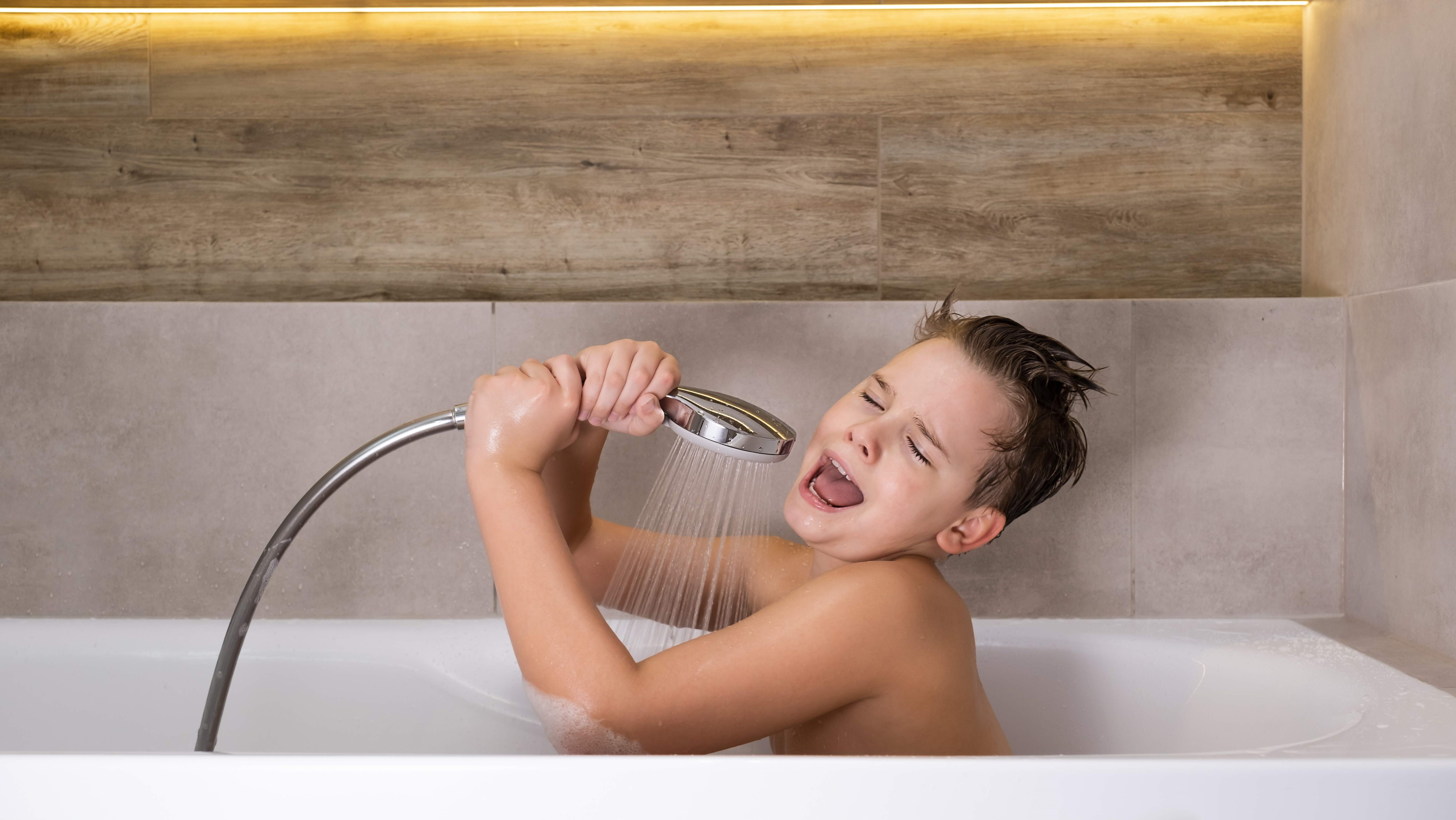 boy in bath with shower head