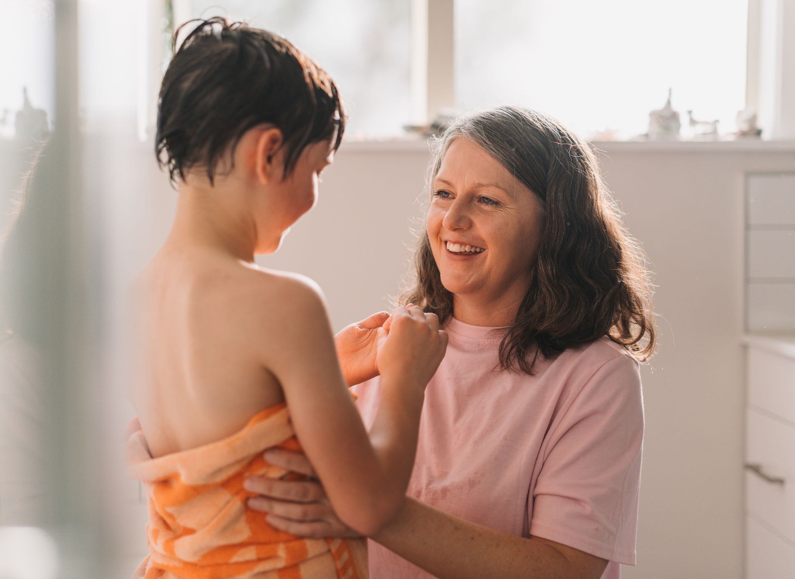 Mother helping son getting ready after bath.