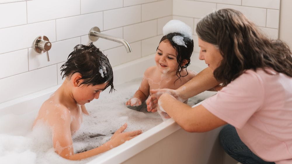 Mother bathing her two children in the bath.
